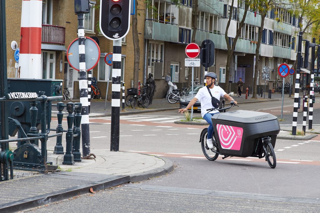 Een persoon die fietst op een cargo bike vrachtfiets in de stad